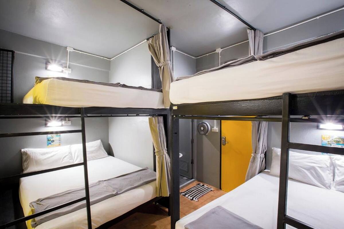 Habitación tipo dormitorio con literas, una ventana pequeña y una puerta con cortina.