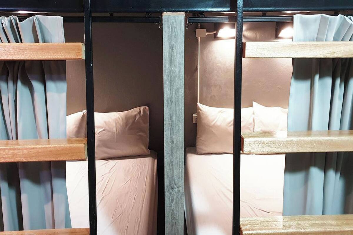 Dormitorio con literas de madera, ropa de cama en tonos claros y cortinas.