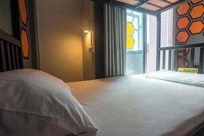 Hotelkamer met een bed, een raam met gordijnen, een wand met een geometrisch patroon en een bordje waarop staat dat de kamer gereserveerd is.