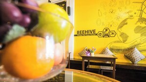 A dining area with a bowl of fruit, a table, and a wall with a bee hive illustration and text.