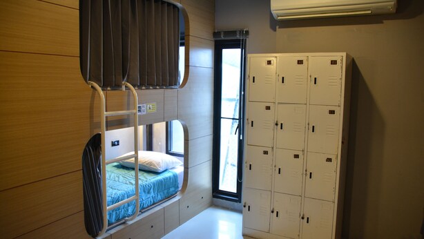 A bunk bed with a window, a set of lockers, and an air conditioning unit. - Hubb Hostel Phuket Airport (Sa Khu)