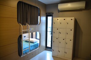 Ein Stockbett mit Fenster, eine Reihe von Schließfächern und eine Klimaanlage.