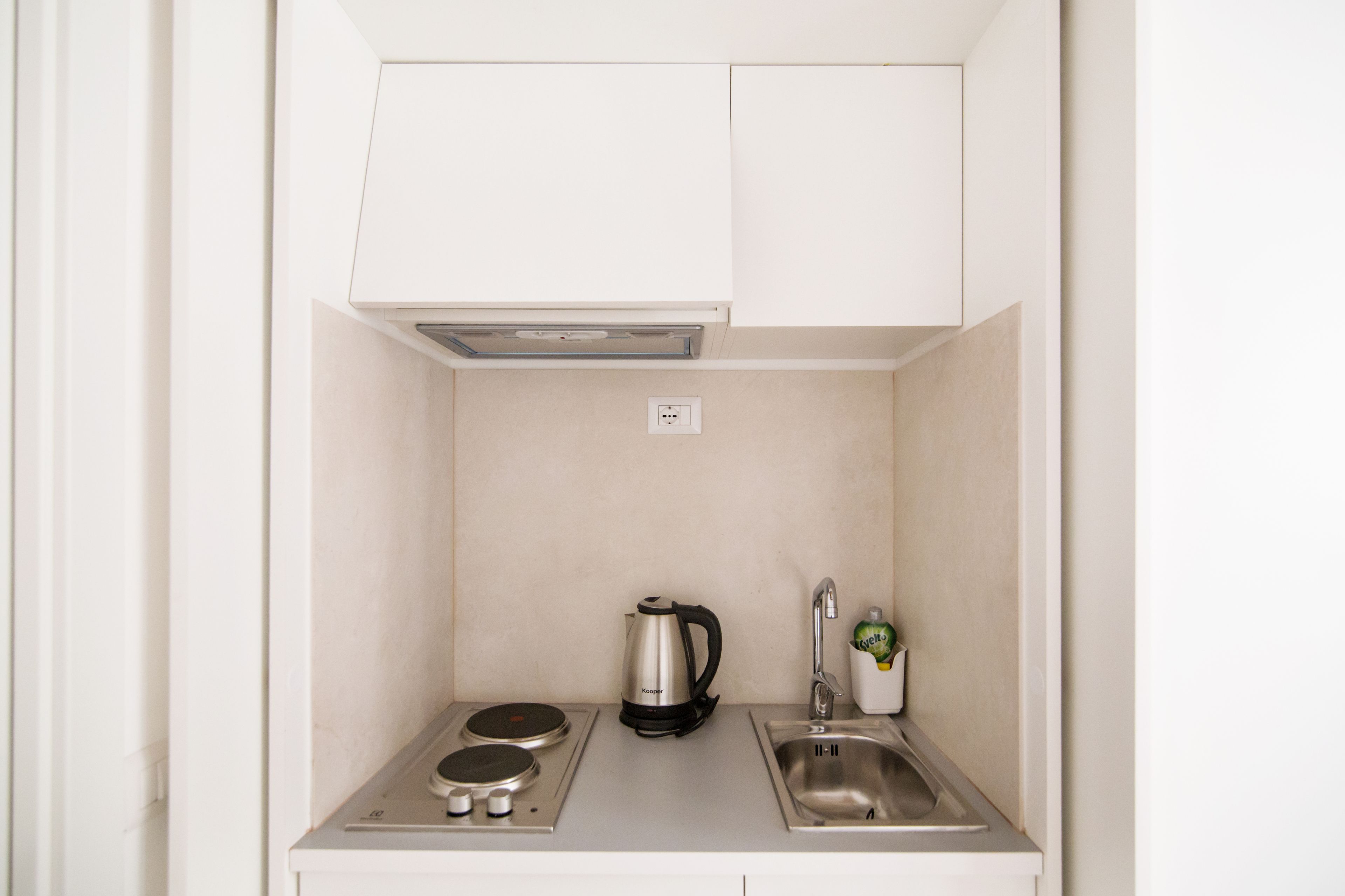 Een kleine keuken met een waterkoker, een koffiezetapparaat en een spoelbak.