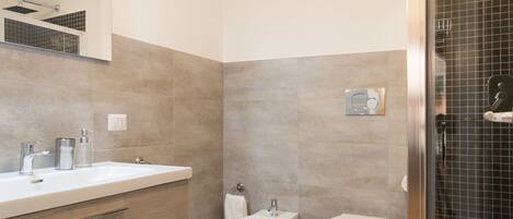 A modern bathroom with a large mirror, a sink, a toilet, and a shower area.
