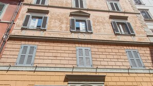 A multi-story building with a classic architectural style, featuring a prominent entrance with a large door and arched windows. - Domenichino Luxury Home (Rome)