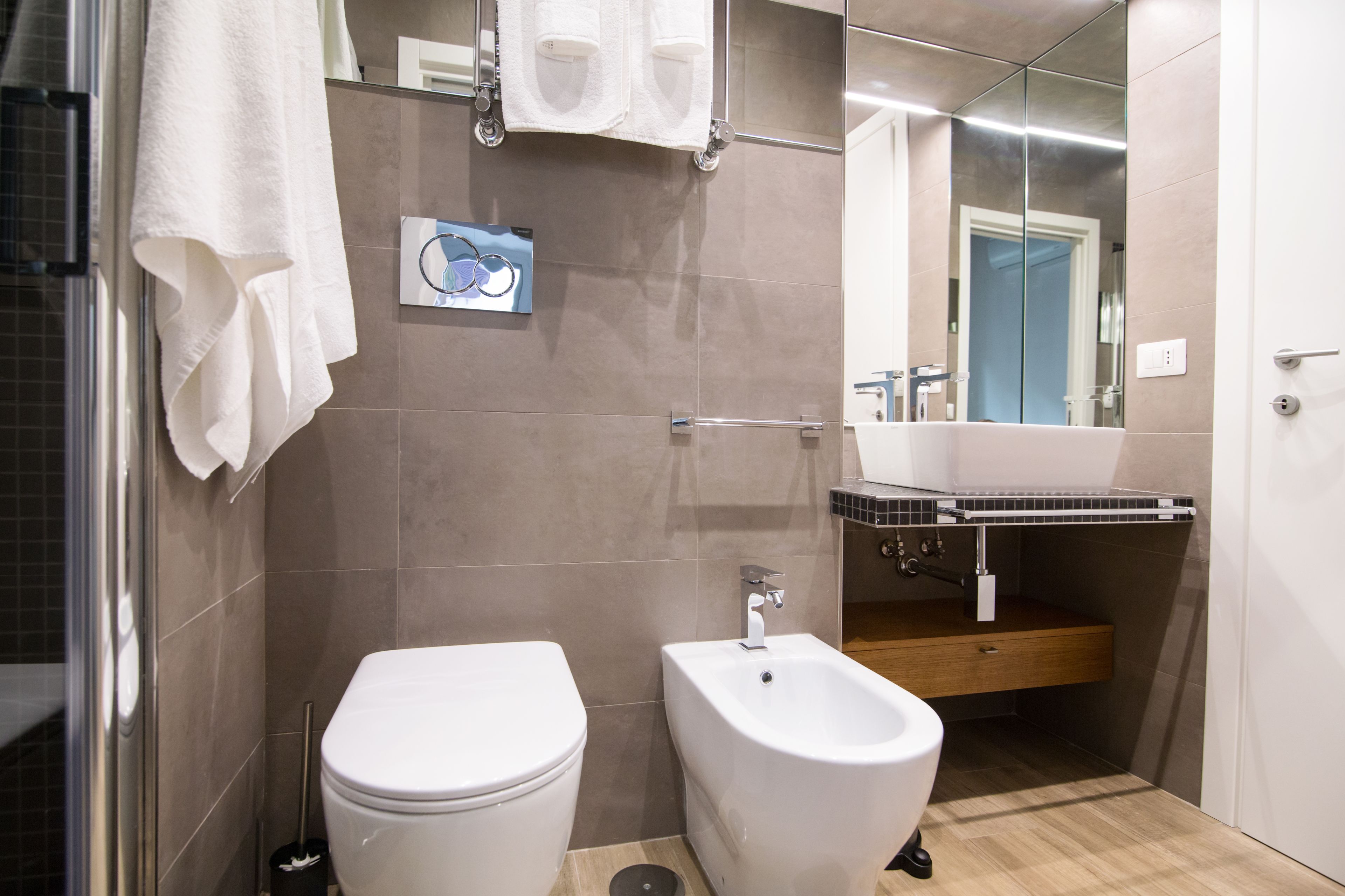 Ein modernes Badezimmer mit Toilette, Bidet und einem Spiegel über dem Waschbecken.