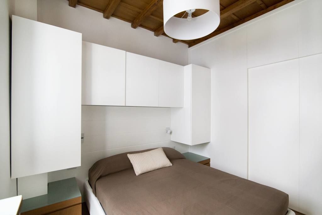 Un dormitorio con cama, mesita de noche, armario e iluminación en el techo.