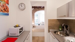 A compact kitchen with a microwave, sink, and a clock on the wall. - Domenichino Luxury Home (Rome)