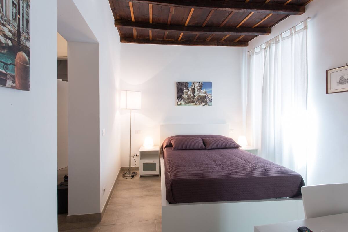 Ein Schlafzimmer mit Bett, Nachttisch, Lampe und einem Gemälde an der Wand.