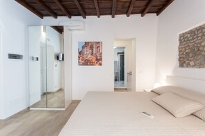 Quarto com cama, espelho, pintura e parede de pedra.