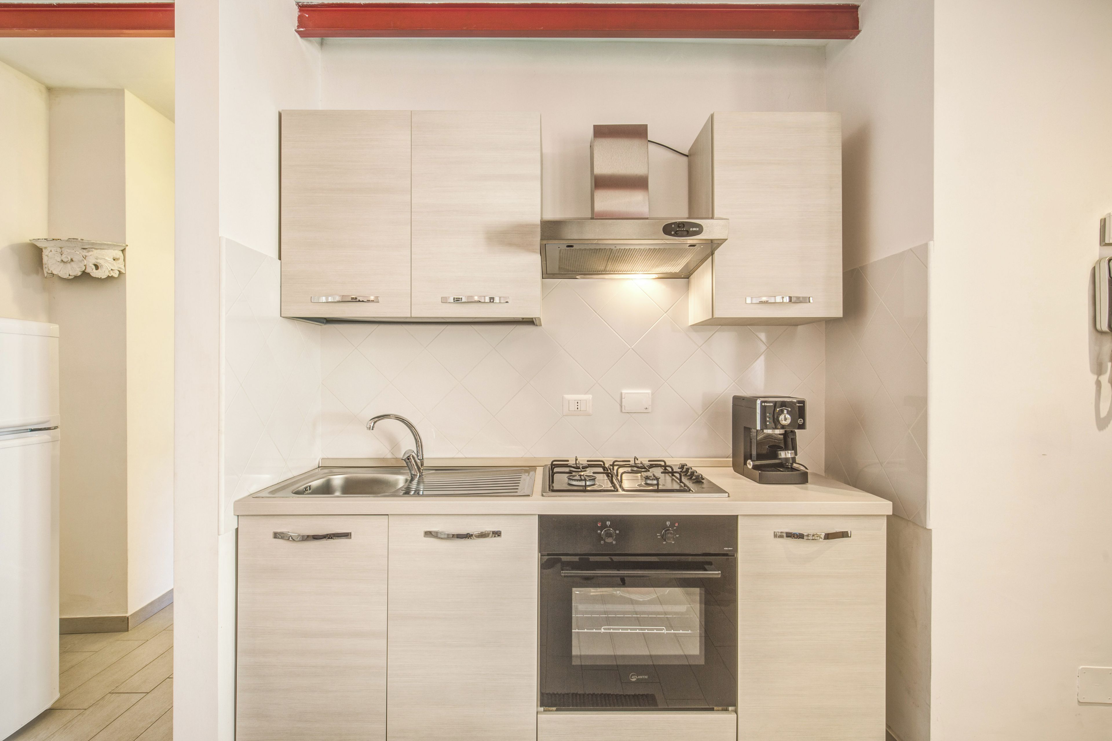 A modern kitchen with a built-in oven, a gas stove, and a coffee maker.