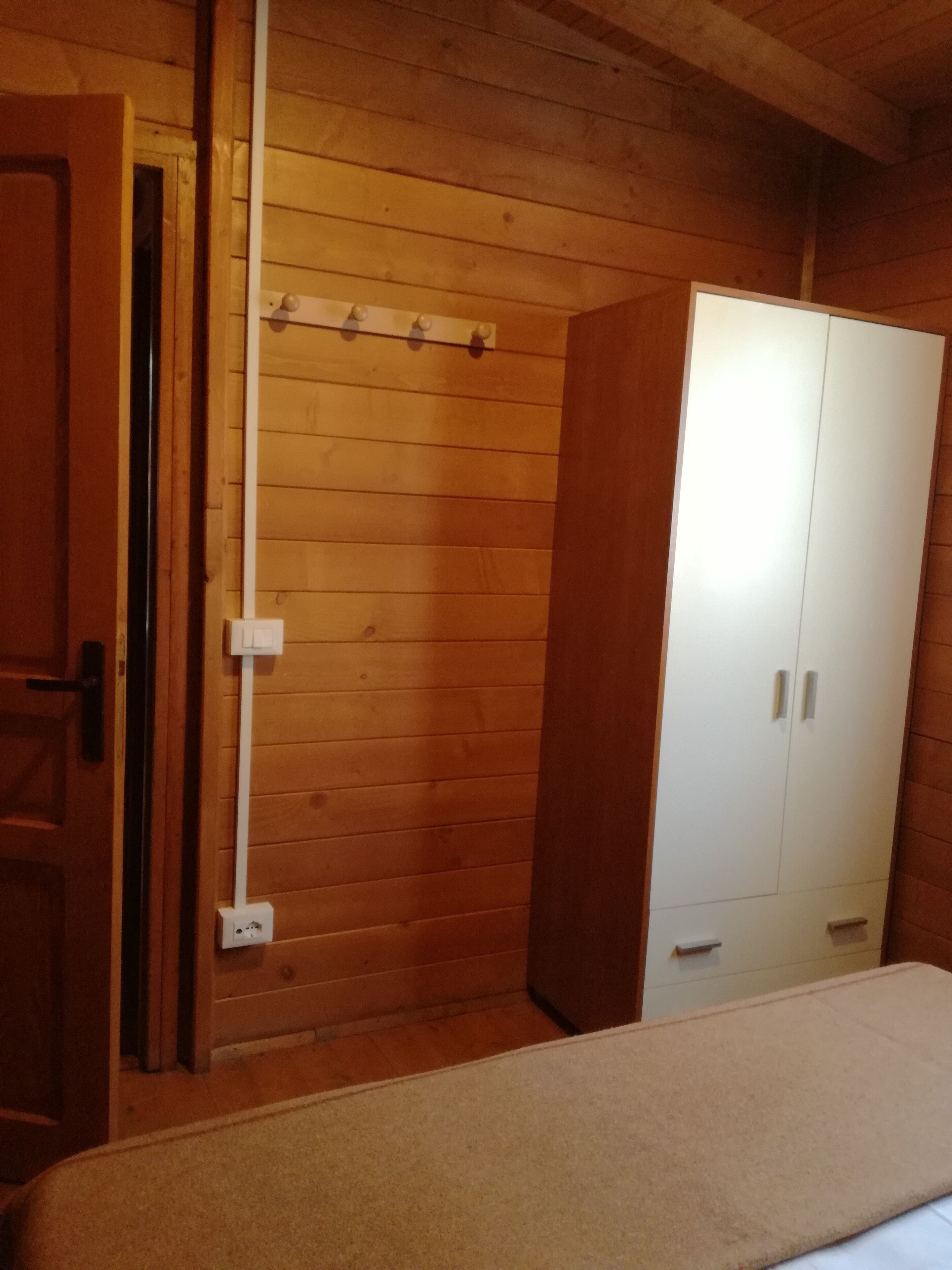 Ein Zimmer mit Holzboden, einem Bett, einem Kleiderschrank und einer Tür.
