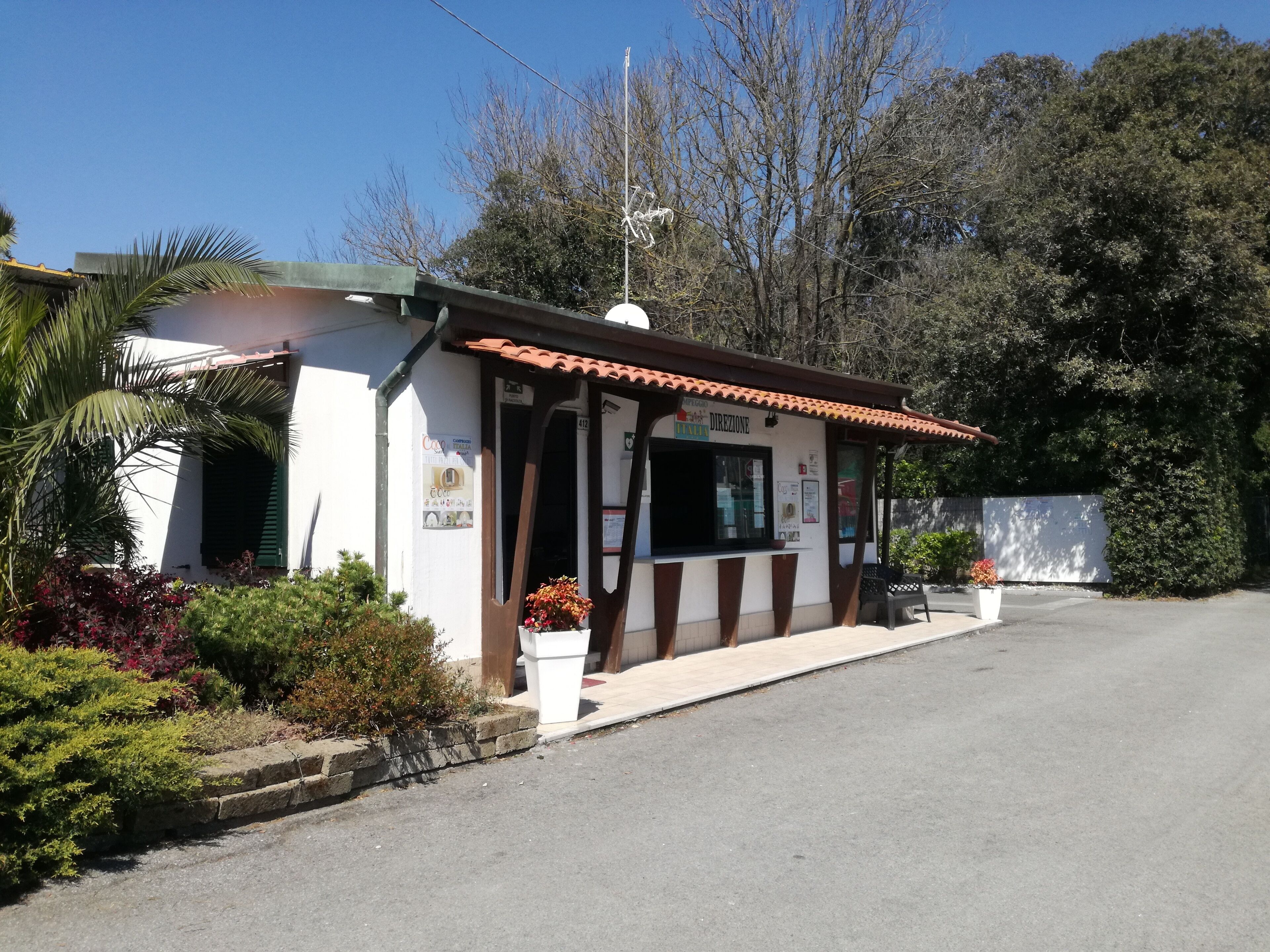 A small, single-story building with a tiled roof, a visible entrance, and a small outdoor seating area with a bench.