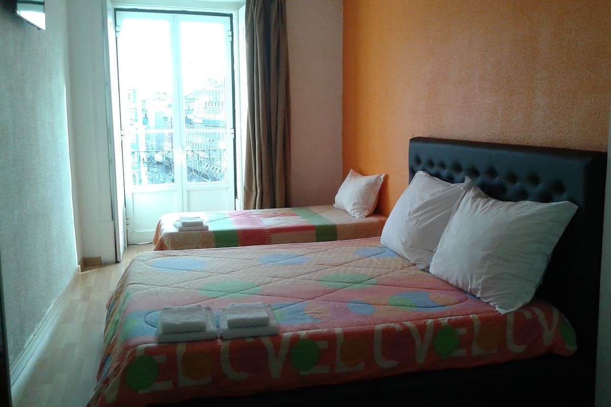 Een hotelkamer met een bed, een raam en uitzicht op gebouwen.