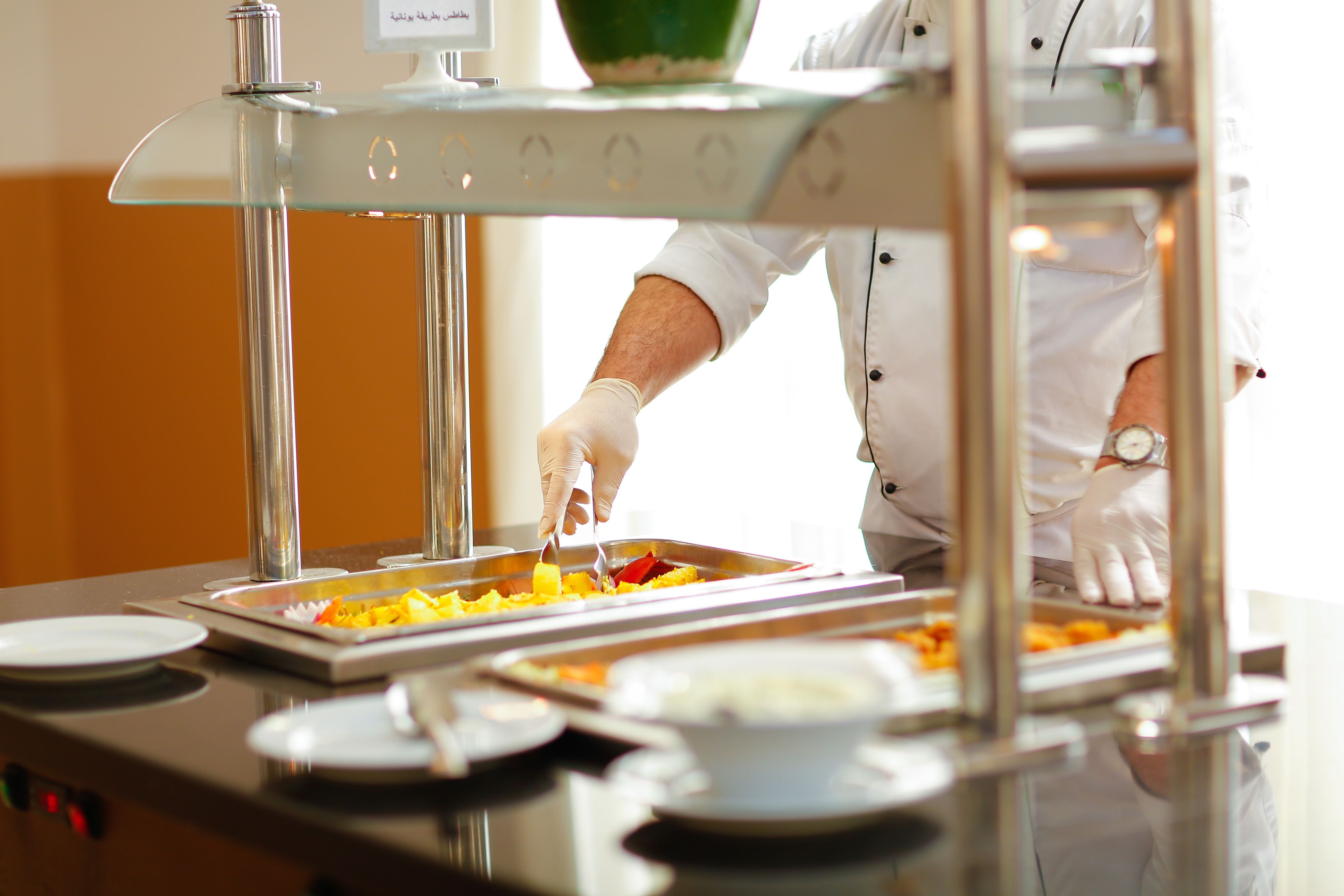 Un buffet allestito con diversi cibi e una persona che serve.