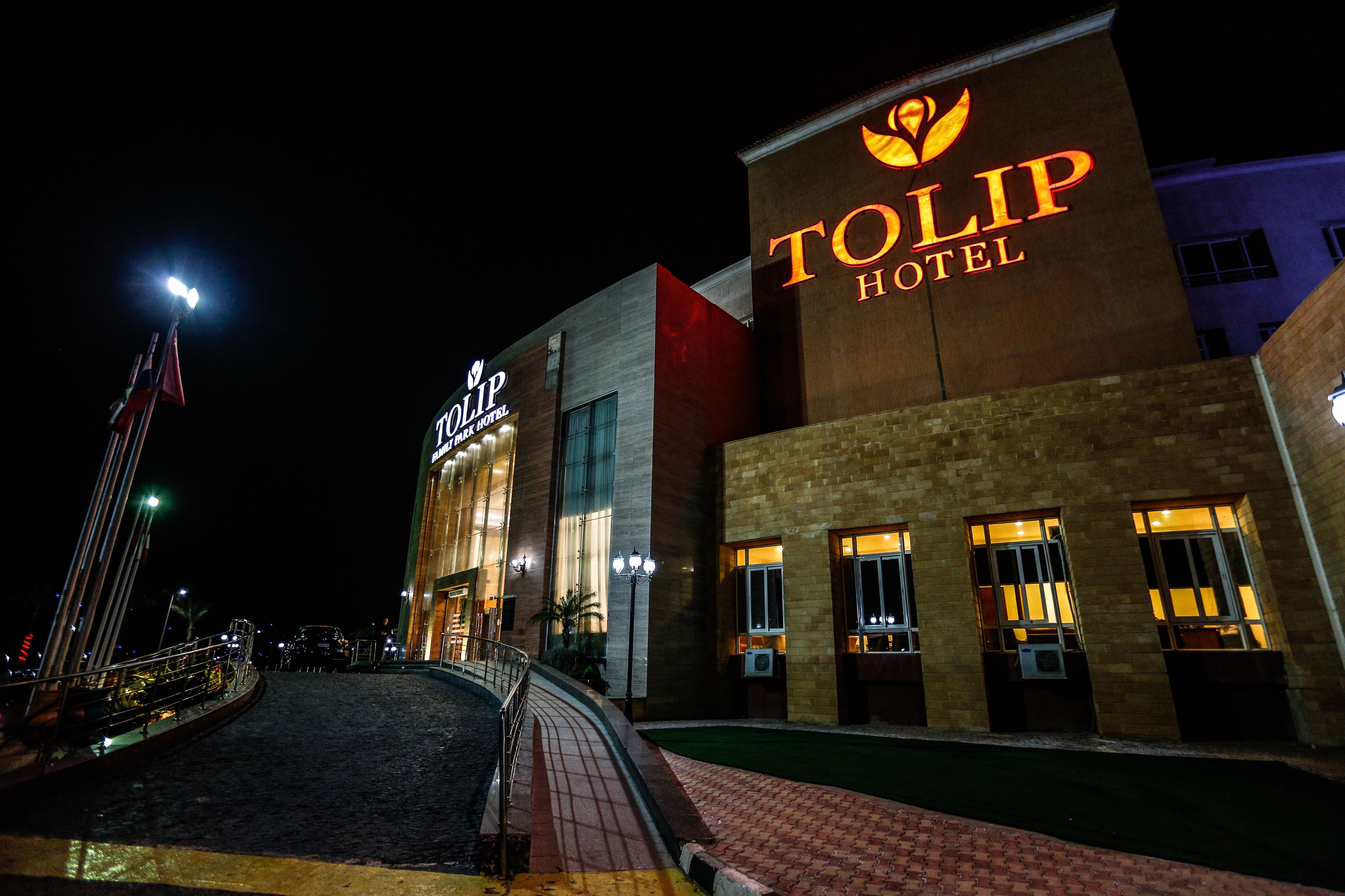 The exterior of the Tolip Hotel at night, featuring its illuminated signage and a well-lit entrance.