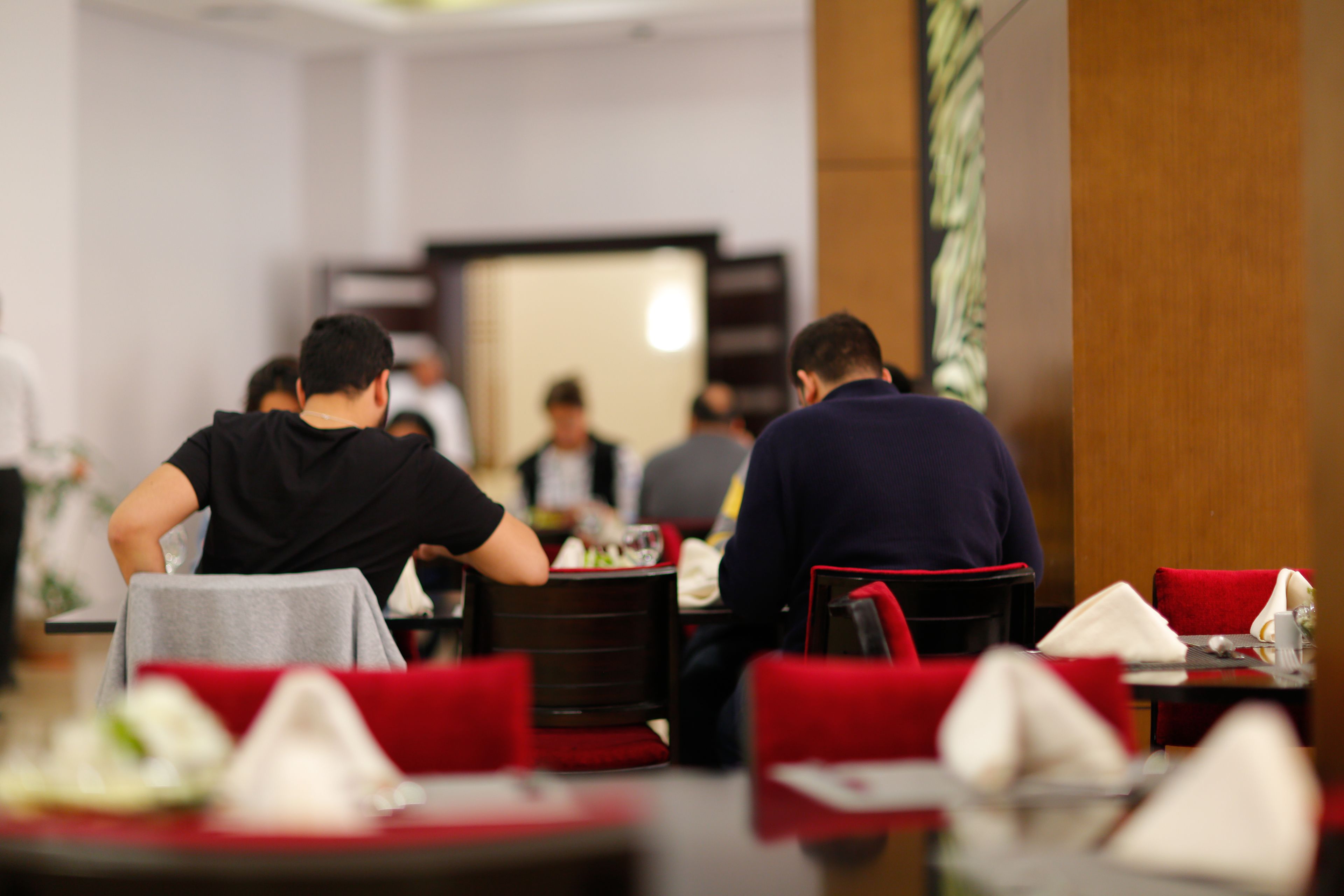 A dining area with tables set for meals, red chairs, and a neutral color scheme.