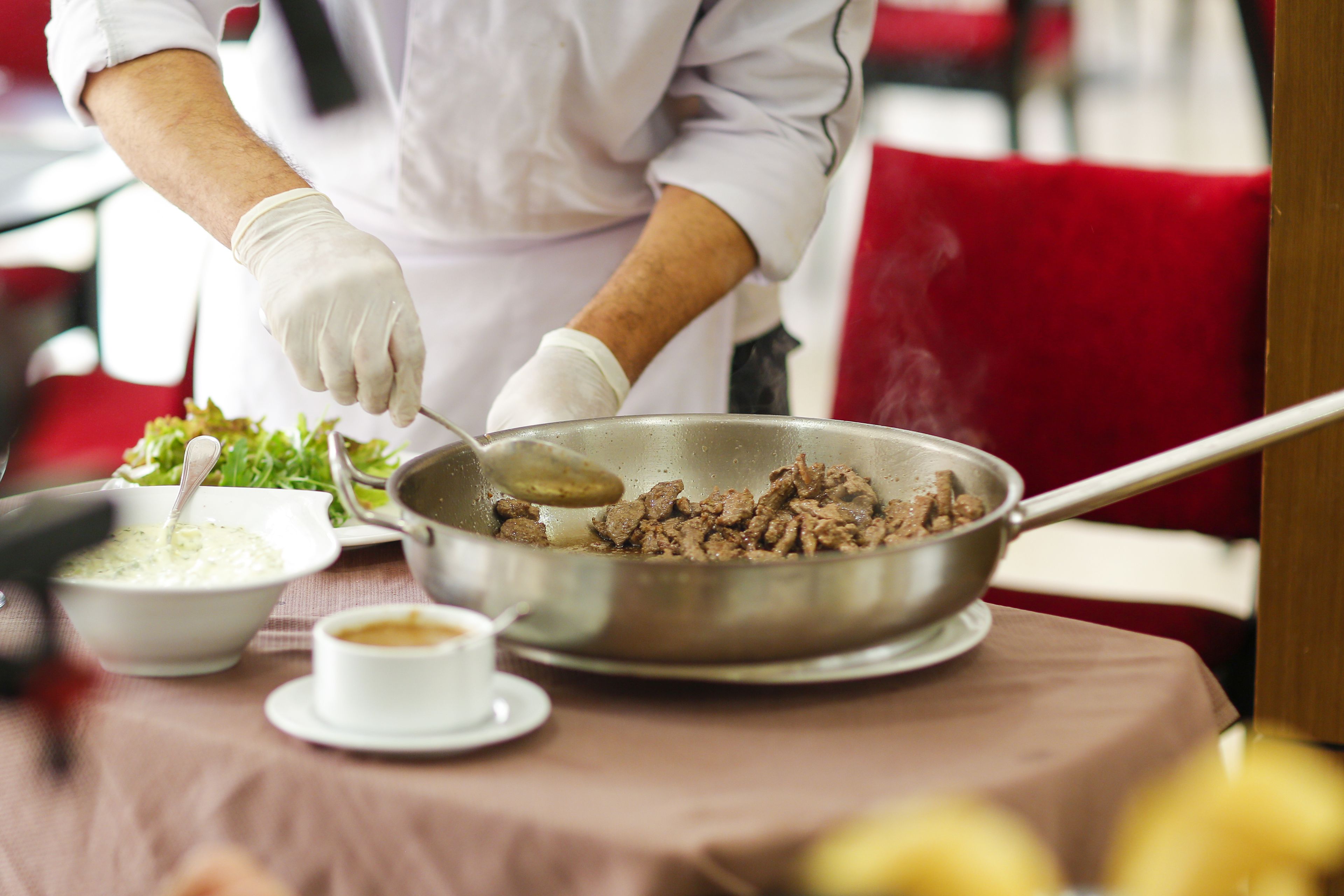 Eine Person kocht in einer Küche, auf dem Tisch steht eine Salatschüssel und eine kleine Schale mit Soße.