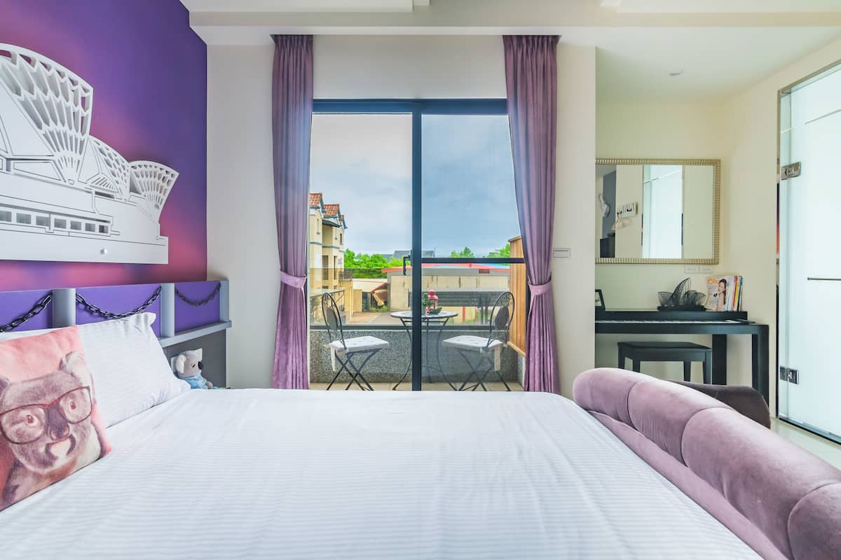A hotel room with a bed, a desk, a chair, and a view of the outside.