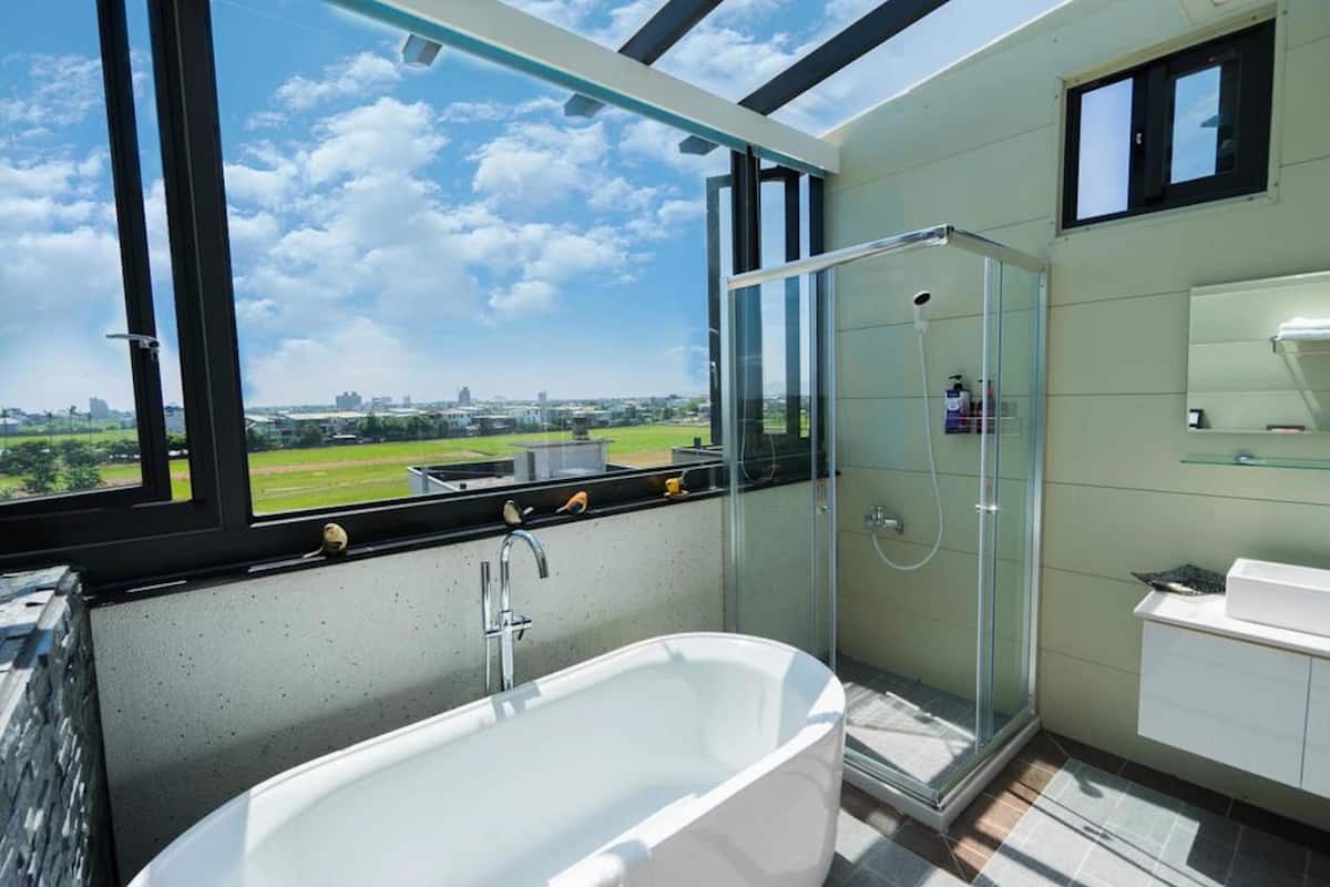 A modern bathroom with a bathtub, shower, and glass-enclosed shower area.