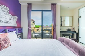 Habitación de hotel con cama, escritorio, silla y vista al exterior.
