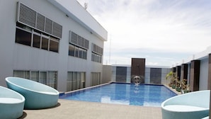 Un edificio moderno con piscina, ventanas amplias y asientos al aire libre.