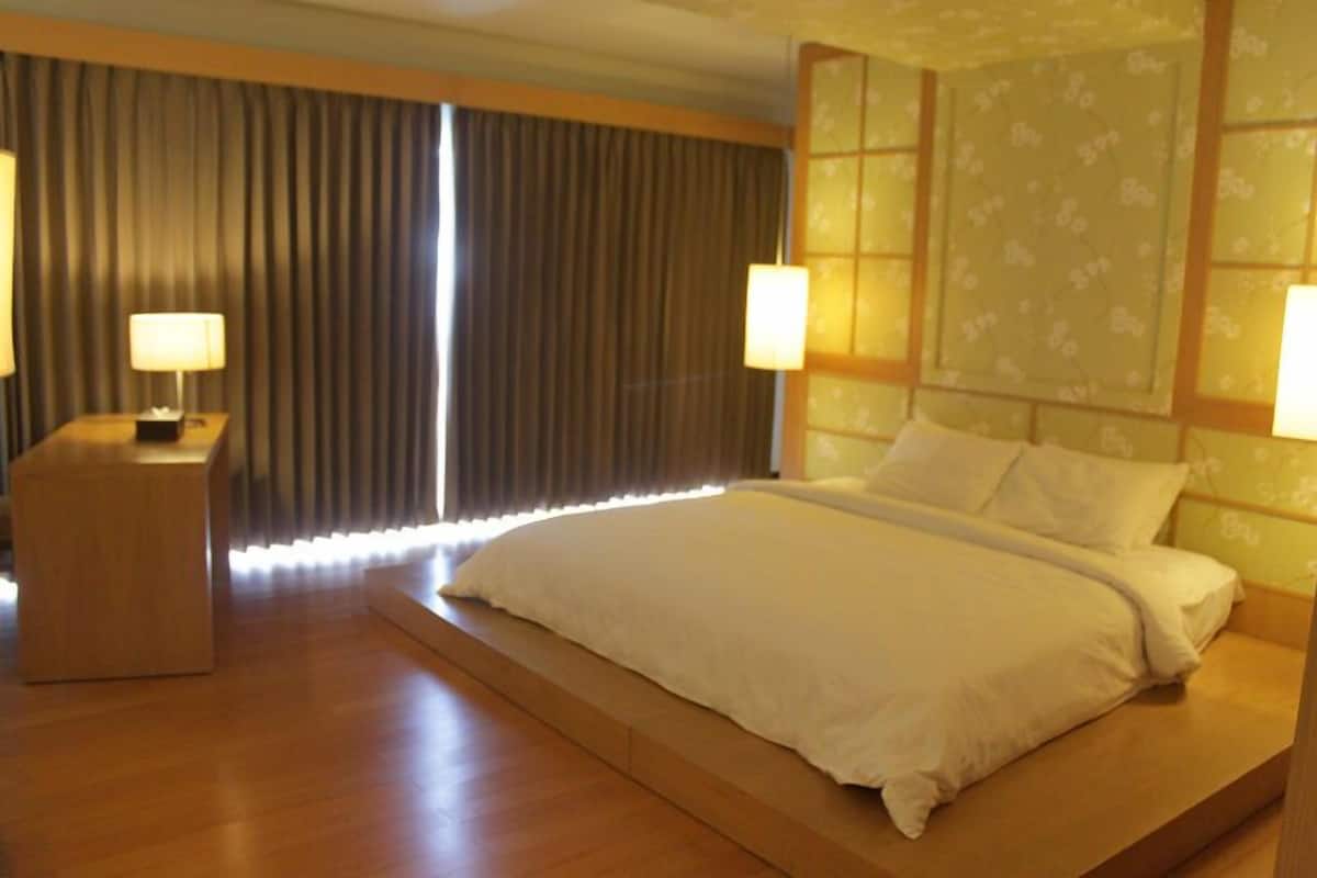 A modern hotel room with a large bed, a bedside table, and a nightstand.