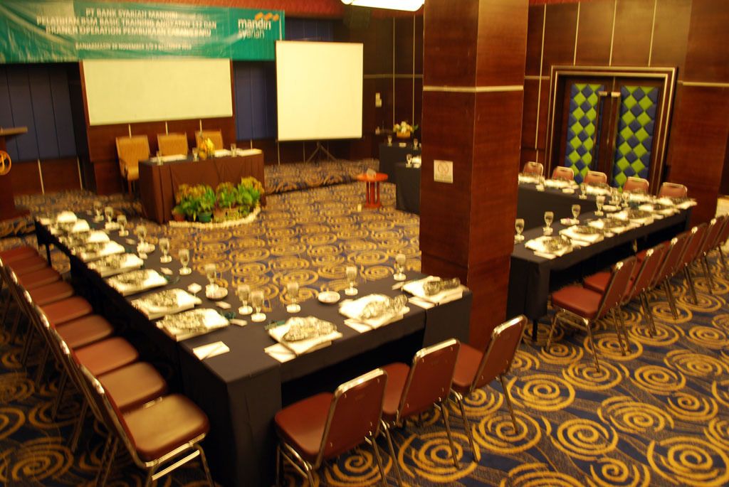 A conference room with a long table set for a meeting, surrounded by chairs.