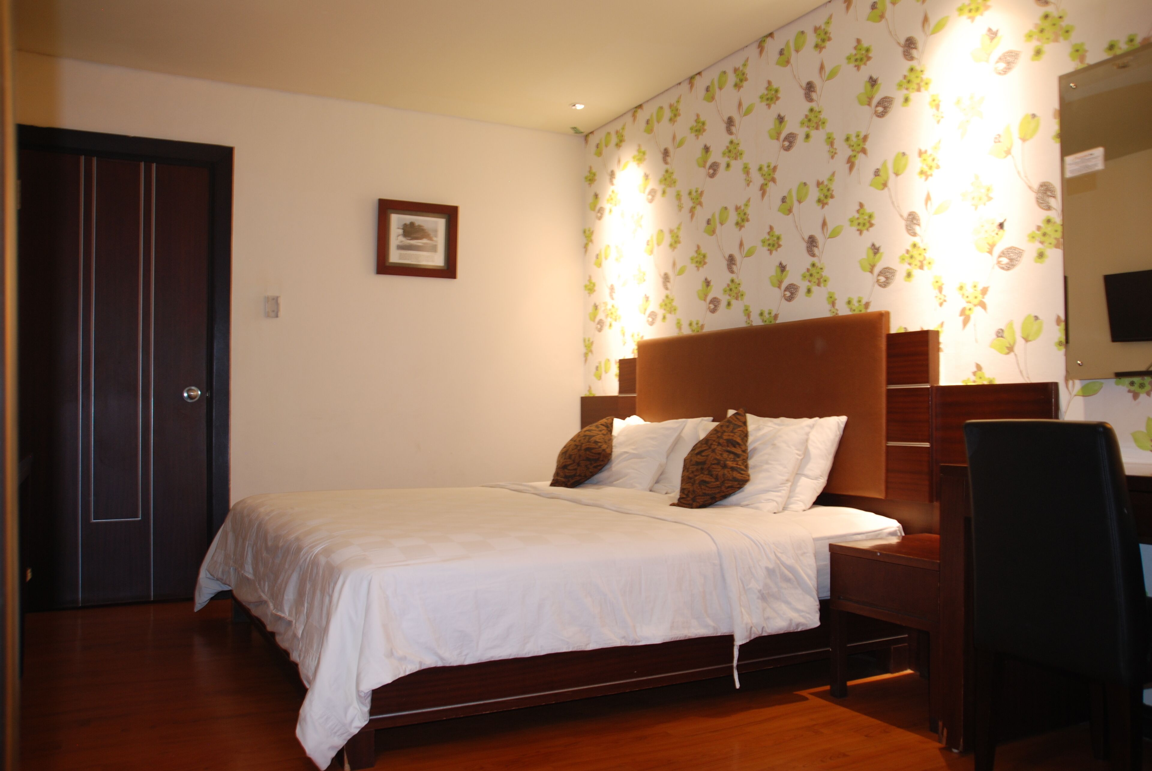 A neatly made bed with a wooden headboard, a bedside table, and a chair.