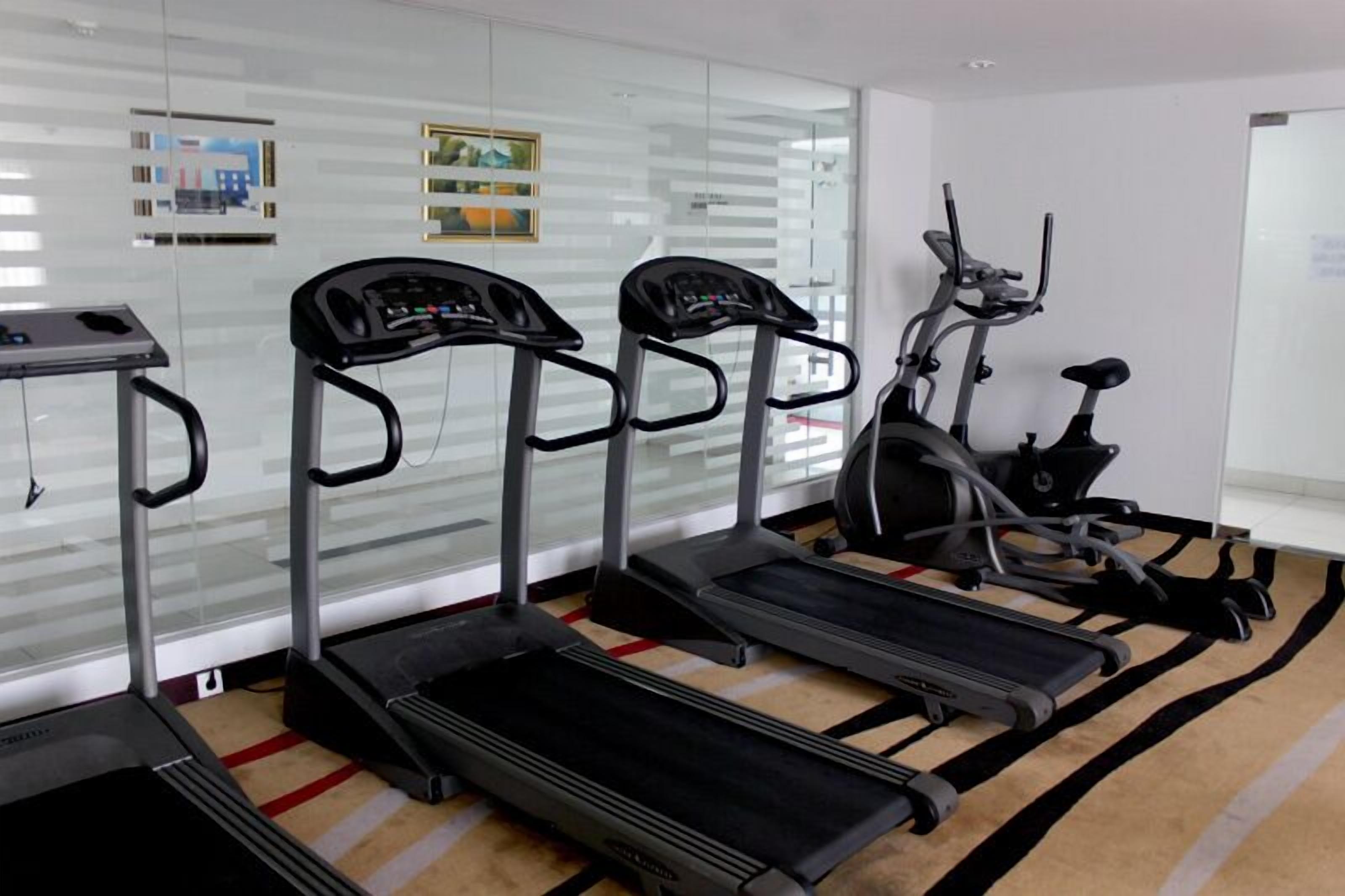 A fitness room with three treadmills and one elliptical machine.