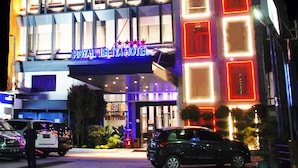 Un hotel con un cartel llamativo que dice "ROYAL JELITA HOTEL" y varias ventanas iluminadas.