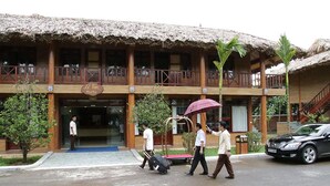 Un bâtiment doté d’un toit de chaume et de balcons en bois, sur lequel on peut lire l’inscription « Le Tan Resort ».
