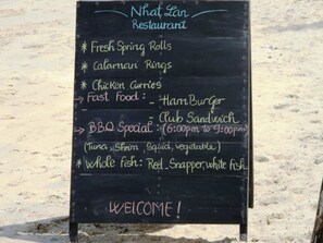 A blackboard menu at Nhat Lan Restaurant listing items like Fresh Spring Rolls, Calamari Rings, Chicken Curries, Fast Food options, BBQ Special, and Whole Fish. - Nhat Lan Resort (Phu Quoc)