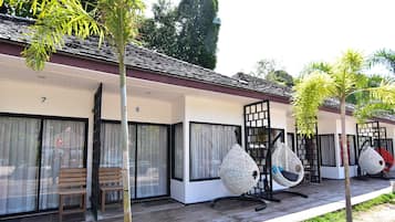 A row of rooms with large windows, wooden benches, and hanging chairs.