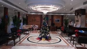 Un vestíbulo con un gran árbol de Navidad, una recepción y una zona de estar con sofás y sillones.
