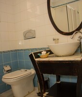 Un baño con inodoro blanco, un lavabo con encimera de mármol y un espejo con marco decorativo.