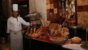 Montaje de bufé con diversos alimentos y un chef con uniforme.