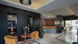 Eine moderne Lobby mit einer Rezeption, einer Sitzecke und einer Treppe zu den oberen Etagen.