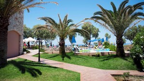 A resort with palm trees, a pool area, and outdoor seating under umbrellas. - Lito Beach (Platanias)