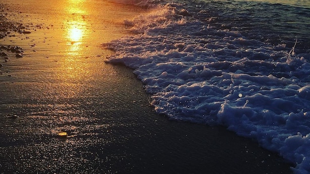 A beach with the sun setting over the water, creating a calm and serene atmosphere. - Lito Beach (Platanias)