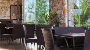 An outdoor dining area with wicker furniture and stone walls. - Lito Beach (Platanias)