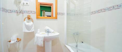Un baño con lavamanos, espejo, toallero, ducha e inodoro.