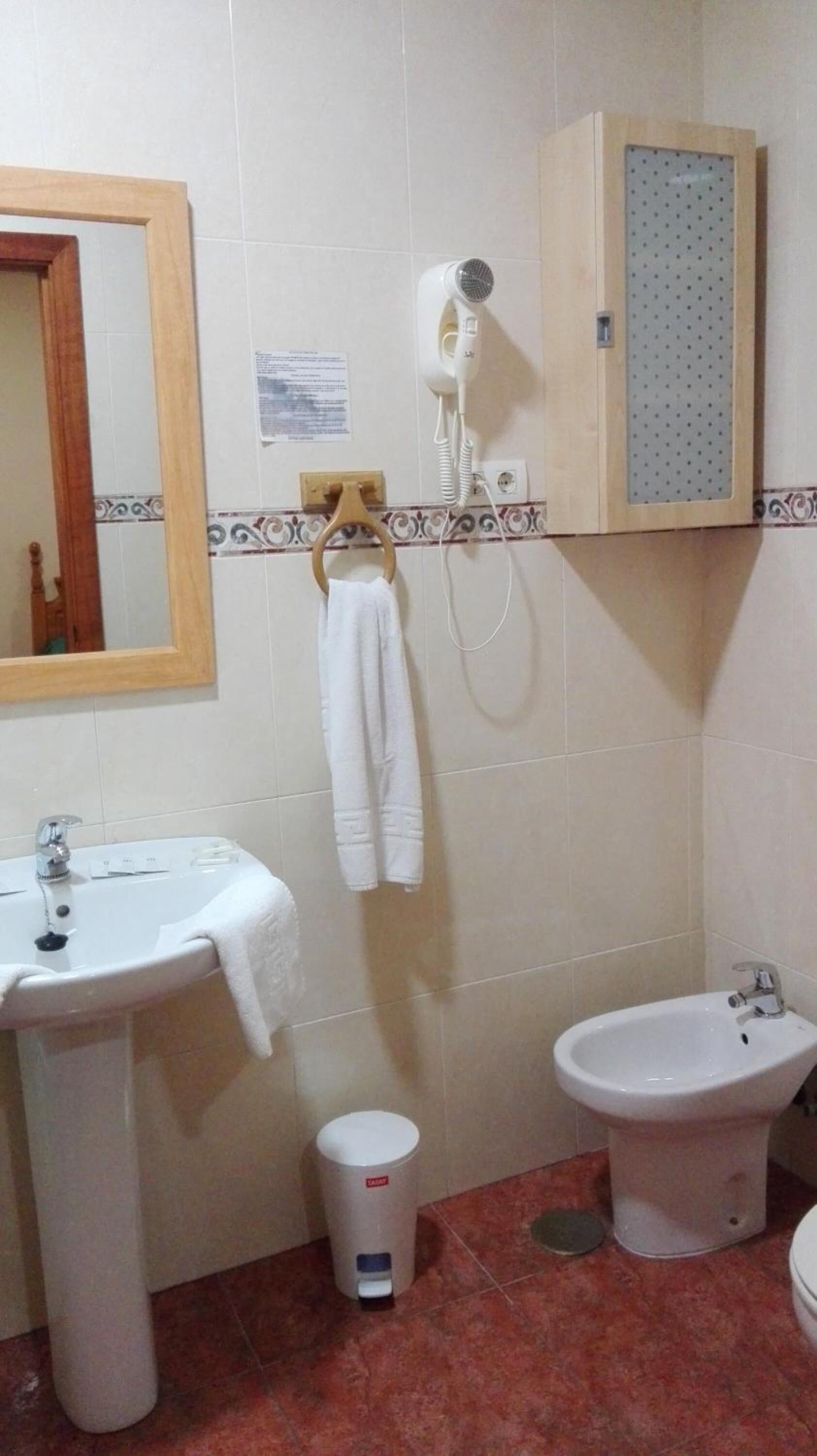 A bathroom with a sink, bidet, and a hairdryer mounted on the wall.