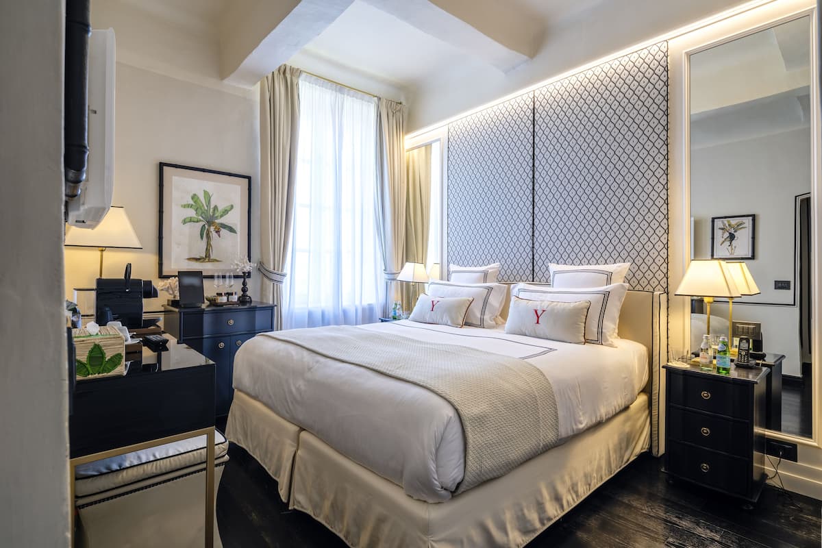 Une chambre d’hôtel avec un grand lit, des tables de chevet, un bureau et une armoire.