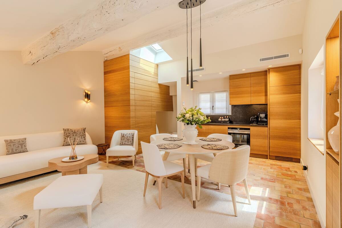 Un salon moderne avec un coin repas, des éléments décoratifs en bois et une cuisine en arrière-plan.