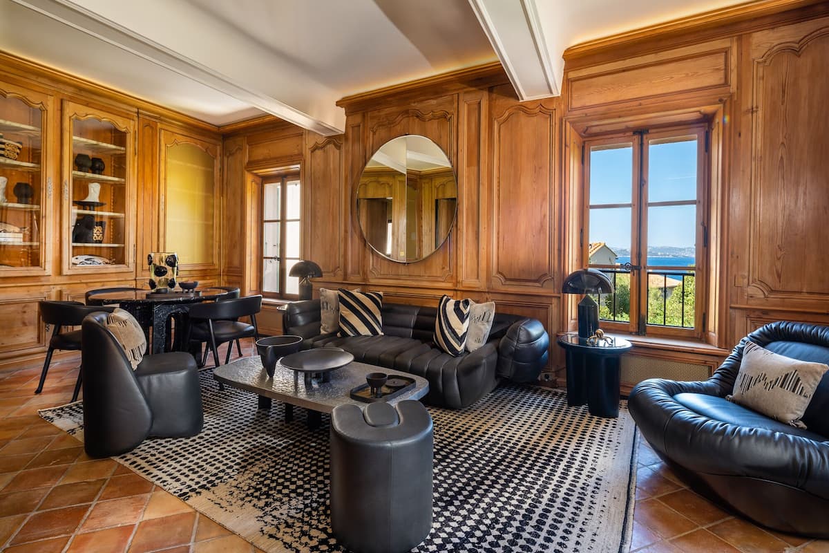 Un salon spacieux avec une cheminée, des canapés en cuir, une table basse et un grand miroir.