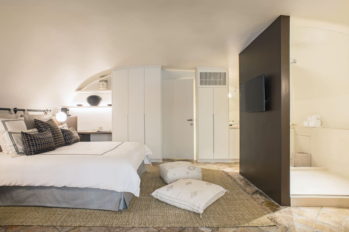 Une chambre à coucher comprenant un lit, une armoire, une télévision et une salle de bain.