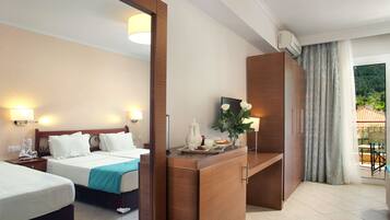 A hotel room with two beds, a wooden desk, a mirror, and a view of the outdoors.