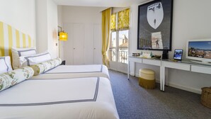 A hotel room with two beds, a desk with a computer, a TV, and a window with curtains. - Hôtel Le Y Saint-Tropez (Saint-Tropez)