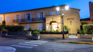 A hotel with a yellow facade, balconies, and a crosswalk in front. - Hôtel Le Y Saint-Tropez (Saint-Tropez)